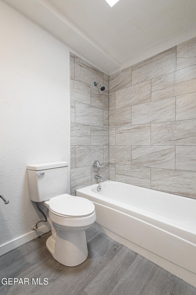 full bathroom with toilet, baseboards, wood finished floors, and bathing tub / shower combination