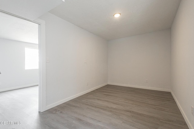 unfurnished room featuring a textured ceiling, baseboards, and wood finished floors