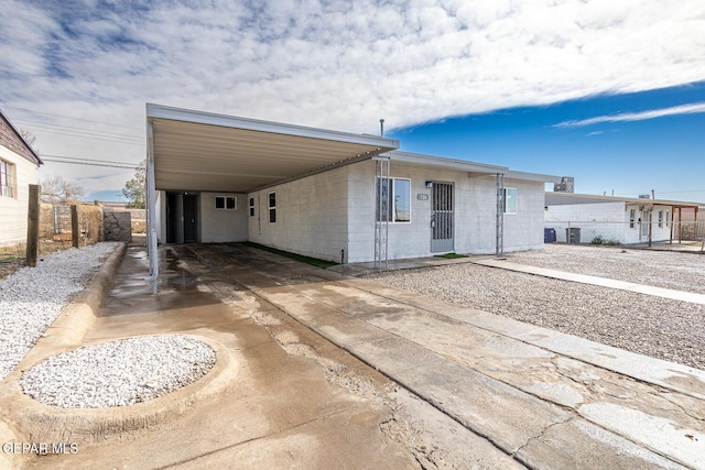 view of front of home featuring driveway, a carport, and fence