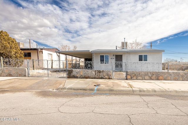 view of front of house featuring concrete driveway, a carport, a fenced front yard, and a gate