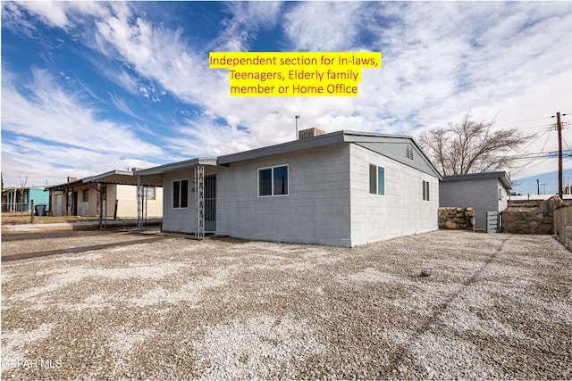 back of house featuring concrete block siding and fence