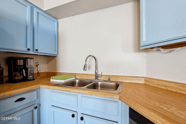 kitchen with stainless steel dishwasher, blue cabinets, and sink