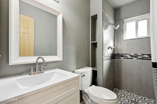 bathroom featuring vanity, toilet, and tiled shower