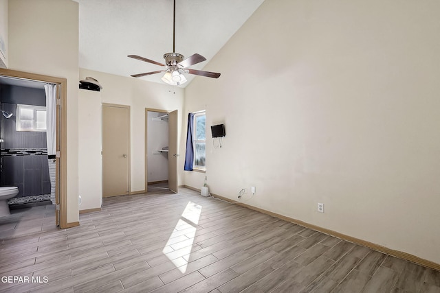 unfurnished bedroom with ceiling fan, ensuite bathroom, and high vaulted ceiling