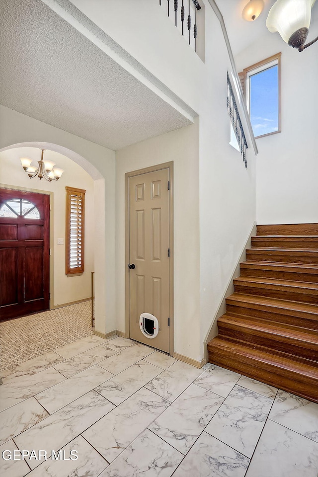 foyer entrance featuring a notable chandelier and a textured ceiling