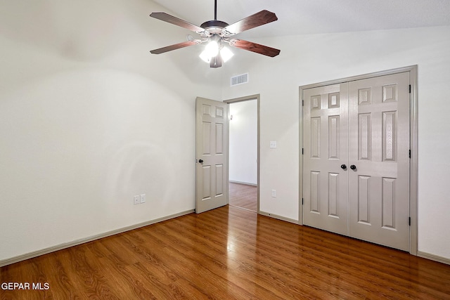 unfurnished bedroom with hardwood / wood-style flooring, vaulted ceiling, ceiling fan, and a closet