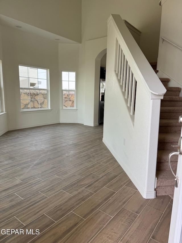 interior space featuring arched walkways, stairway, baseboards, and wood tiled floor