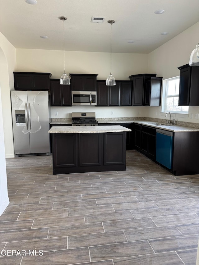 kitchen featuring visible vents, wood finish floors, a sink, stainless steel appliances, and a center island