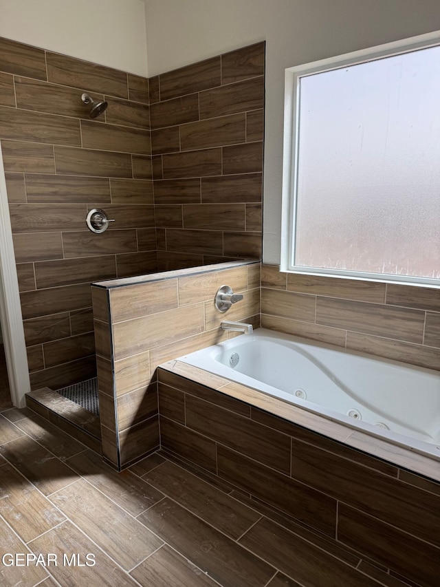 bathroom featuring a tile shower and a tub with jets