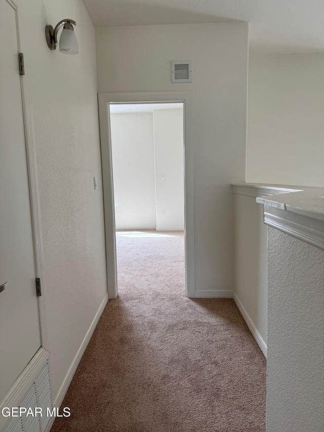 hall with visible vents, baseboards, and carpet floors