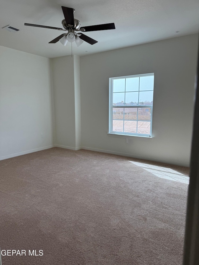 carpeted empty room featuring visible vents, baseboards, and a ceiling fan