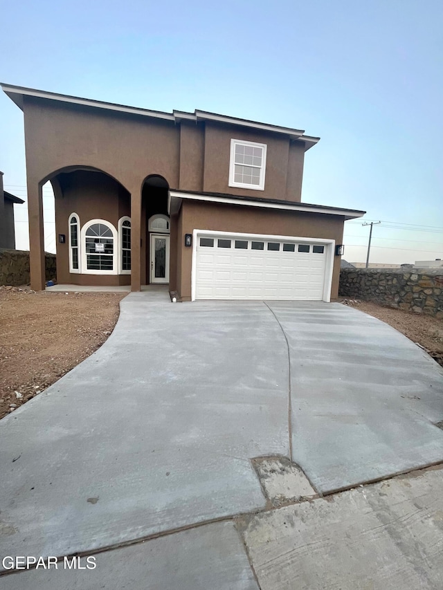 view of front of home with stucco siding, a garage, and driveway