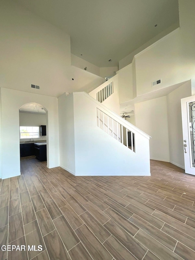 spare room with arched walkways, visible vents, a towering ceiling, and wood tiled floor