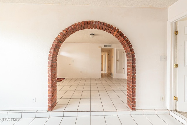 corridor featuring light tile patterned floors and a textured ceiling