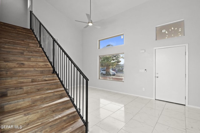 foyer with ceiling fan and a towering ceiling