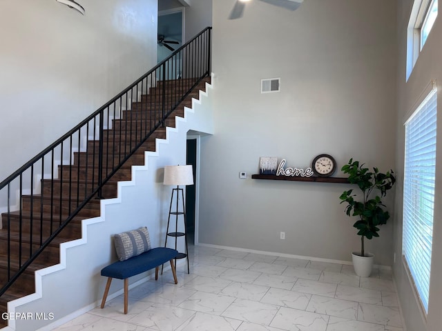 stairs featuring ceiling fan, a towering ceiling, and a wealth of natural light