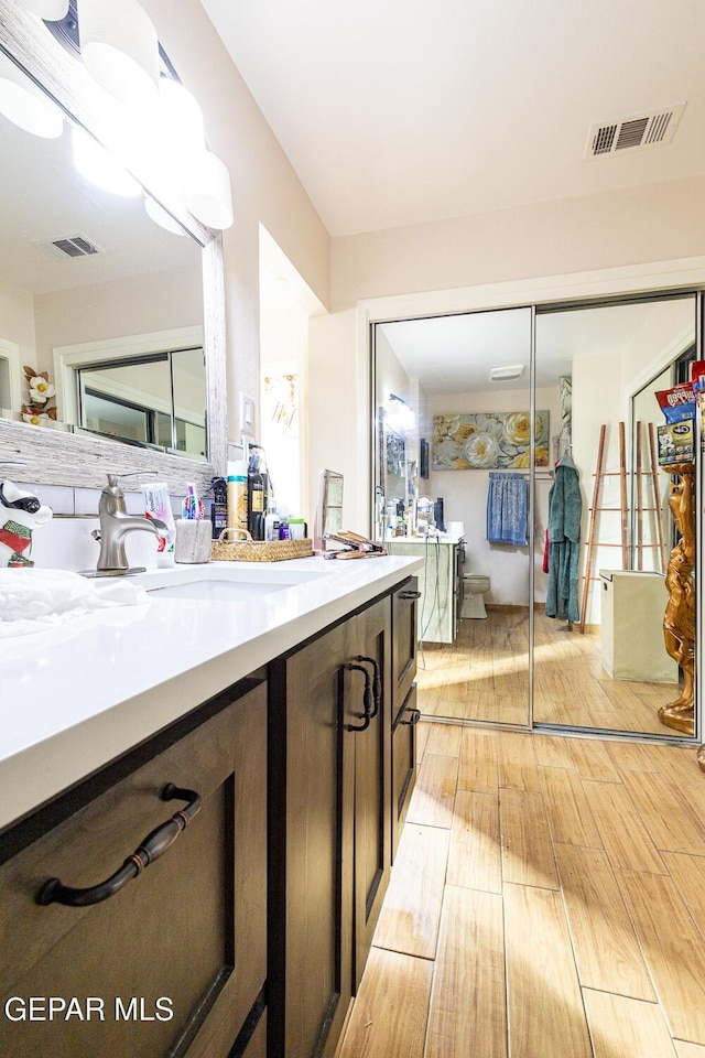 bathroom with vanity, toilet, and hardwood / wood-style floors