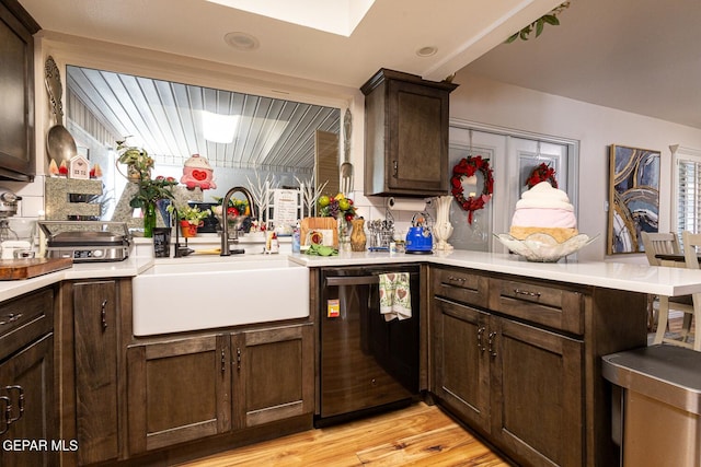 kitchen with kitchen peninsula, dishwasher, sink, dark brown cabinetry, and light hardwood / wood-style floors