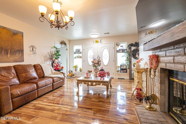 living room with a large fireplace, a notable chandelier, and light hardwood / wood-style flooring