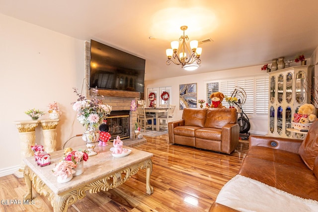 living room featuring light hardwood / wood-style floors, a large fireplace, and a chandelier