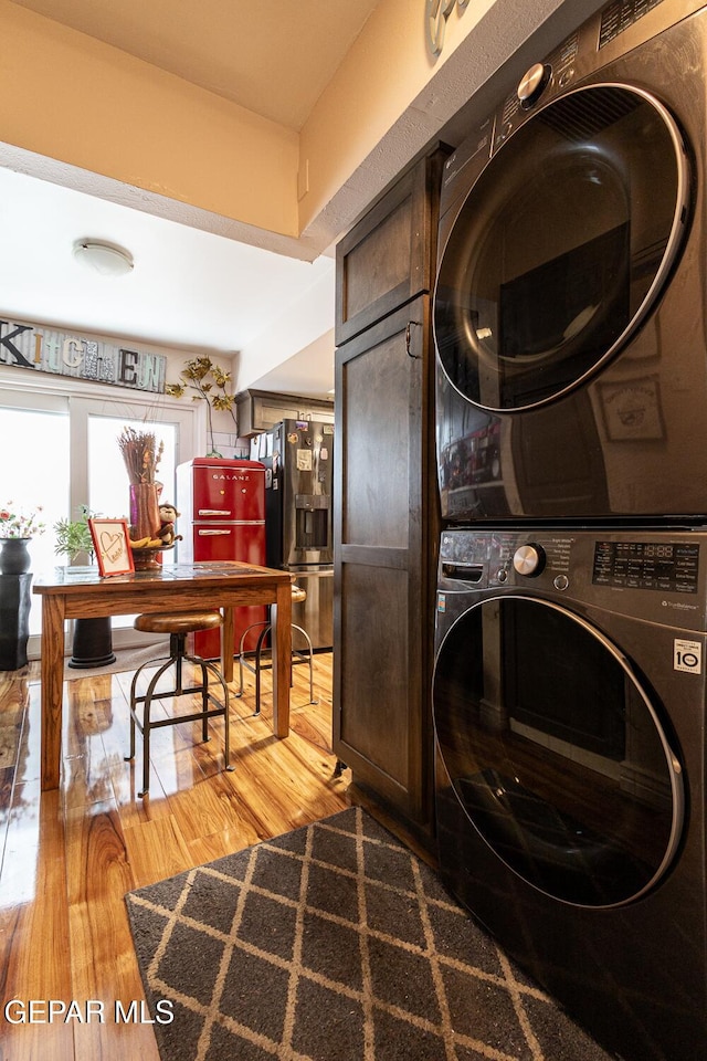 laundry room with stacked washer / drying machine and hardwood / wood-style floors