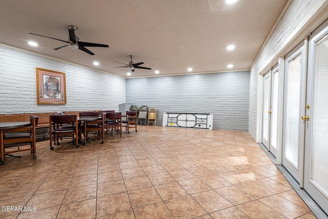 dining space featuring brick wall, light tile patterned floors, and a textured ceiling