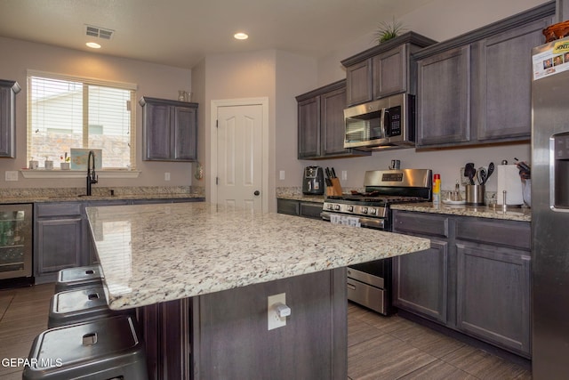 kitchen with a breakfast bar, stainless steel appliances, a center island, wine cooler, and dark brown cabinetry