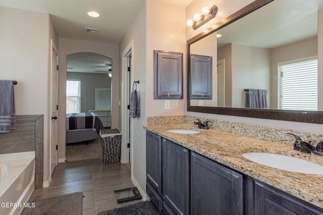 bathroom featuring vanity, a washtub, and ceiling fan