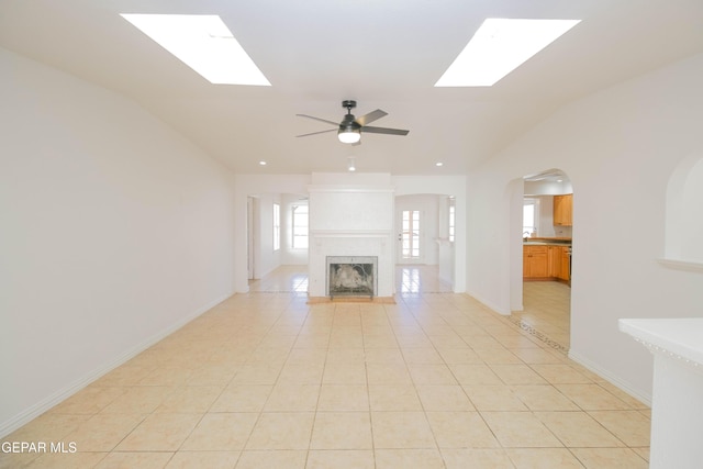 unfurnished living room featuring a multi sided fireplace, lofted ceiling, light tile patterned floors, and ceiling fan