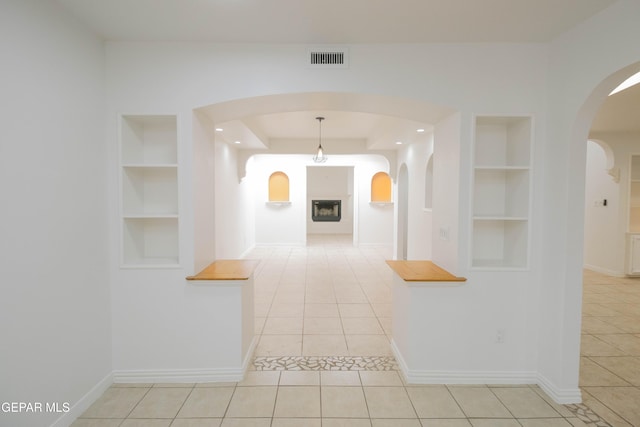 hall with light tile patterned floors and built in shelves