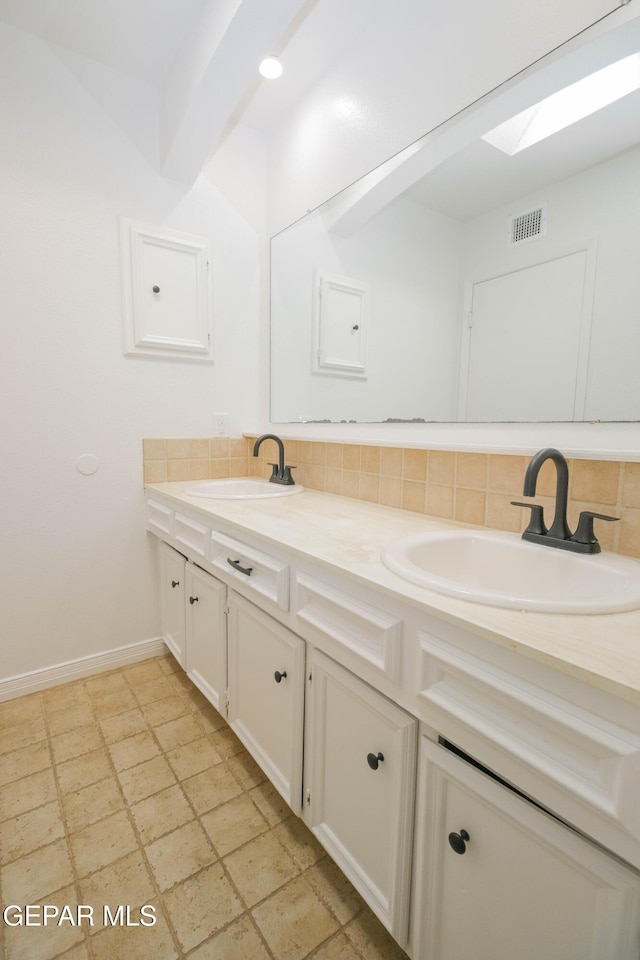 bathroom featuring vanity, backsplash, and a skylight