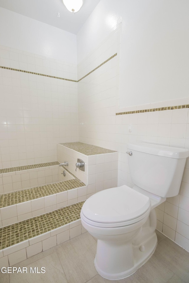 bathroom with tile patterned floors, toilet, and tile walls