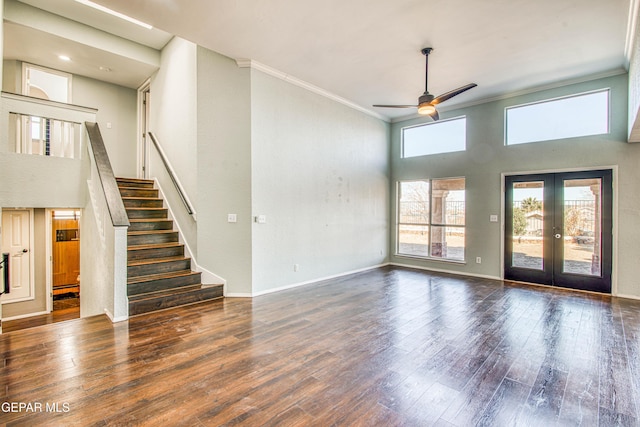 unfurnished living room with french doors, ornamental molding, dark hardwood / wood-style flooring, ceiling fan, and a high ceiling