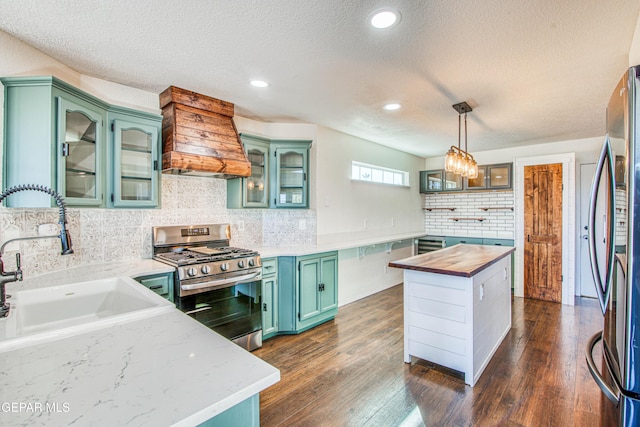 kitchen with pendant lighting, sink, butcher block countertops, stainless steel appliances, and dark hardwood / wood-style flooring