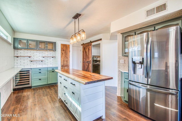 kitchen with butcher block counters, stainless steel fridge with ice dispenser, dark hardwood / wood-style floors, and a barn door