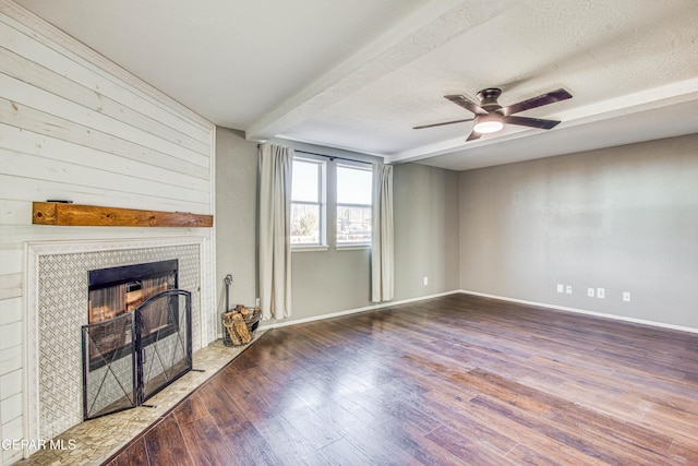 unfurnished living room with hardwood / wood-style flooring, ceiling fan, a tile fireplace, and a textured ceiling