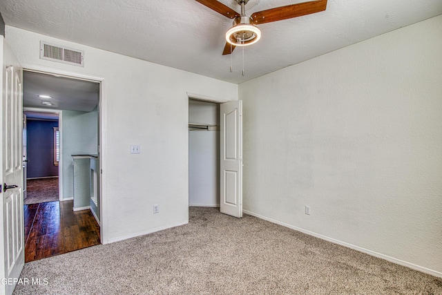 unfurnished bedroom featuring ceiling fan, carpet flooring, a closet, and a textured ceiling