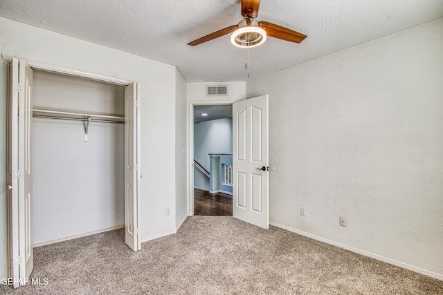 unfurnished bedroom with ceiling fan, carpet, a textured ceiling, and a closet