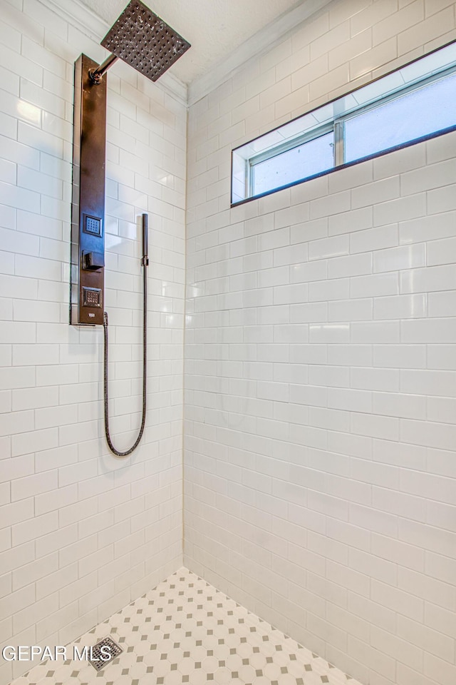 bathroom featuring ornamental molding and tiled shower