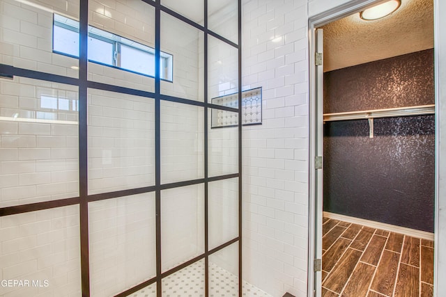 bathroom with a textured ceiling and tiled shower