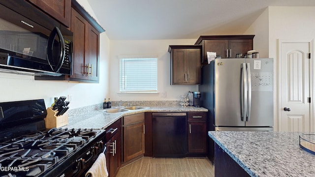 kitchen with light stone countertops, sink, dark brown cabinetry, and black appliances