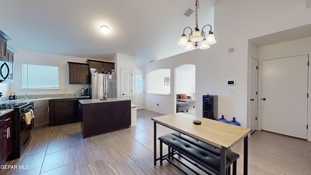 kitchen with light stone counters, an inviting chandelier, a center island, hanging light fixtures, and black appliances