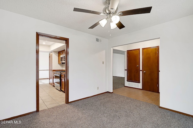 carpeted spare room with ceiling fan and a textured ceiling