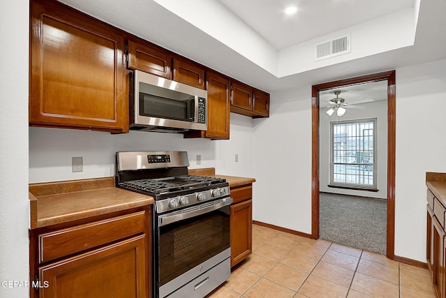 kitchen with stainless steel appliances, light tile patterned floors, and ceiling fan