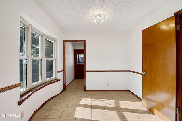 tiled empty room with a textured ceiling