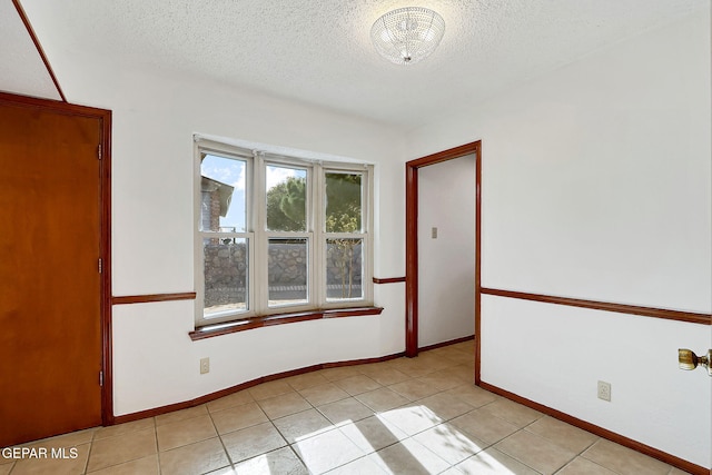 empty room featuring light tile patterned flooring and a textured ceiling