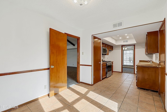 kitchen featuring stainless steel appliances, sink, a textured ceiling, and light tile patterned floors