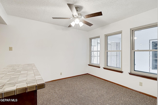 carpeted empty room featuring ceiling fan and a textured ceiling