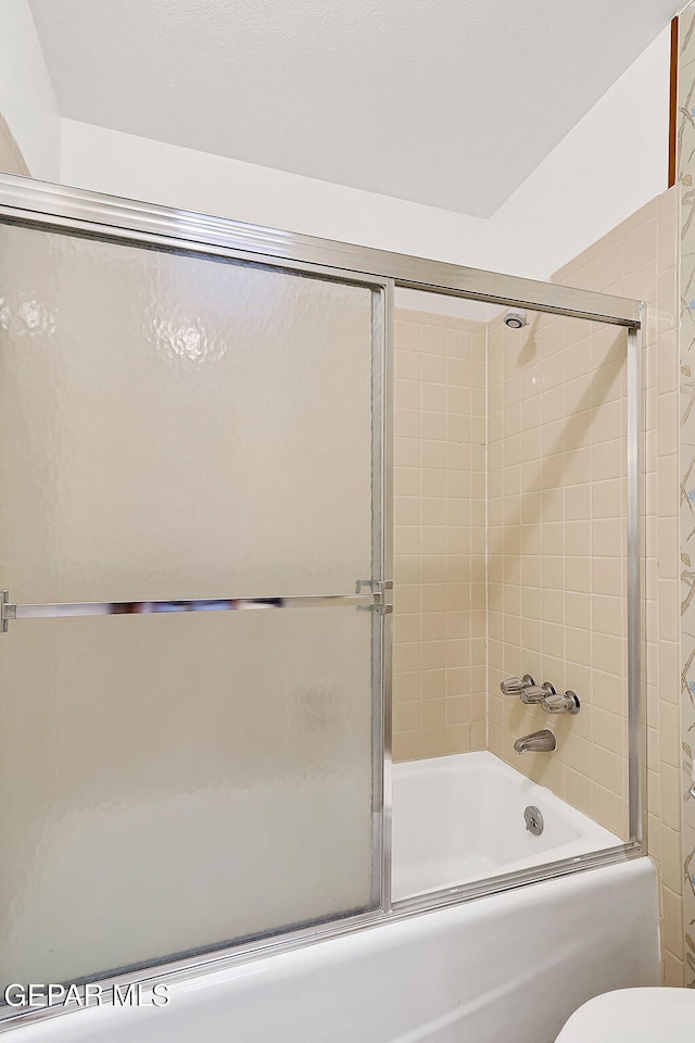 bathroom featuring toilet and bath / shower combo with glass door