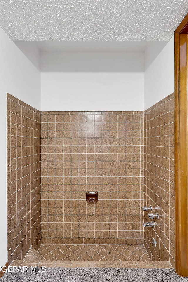 bathroom with a tile shower and a textured ceiling